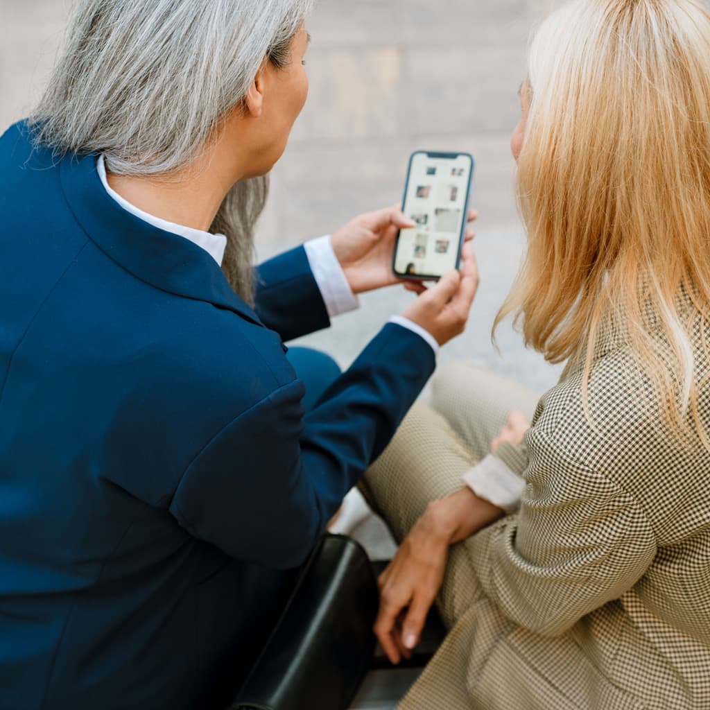 Two women outside looking at a cell phone