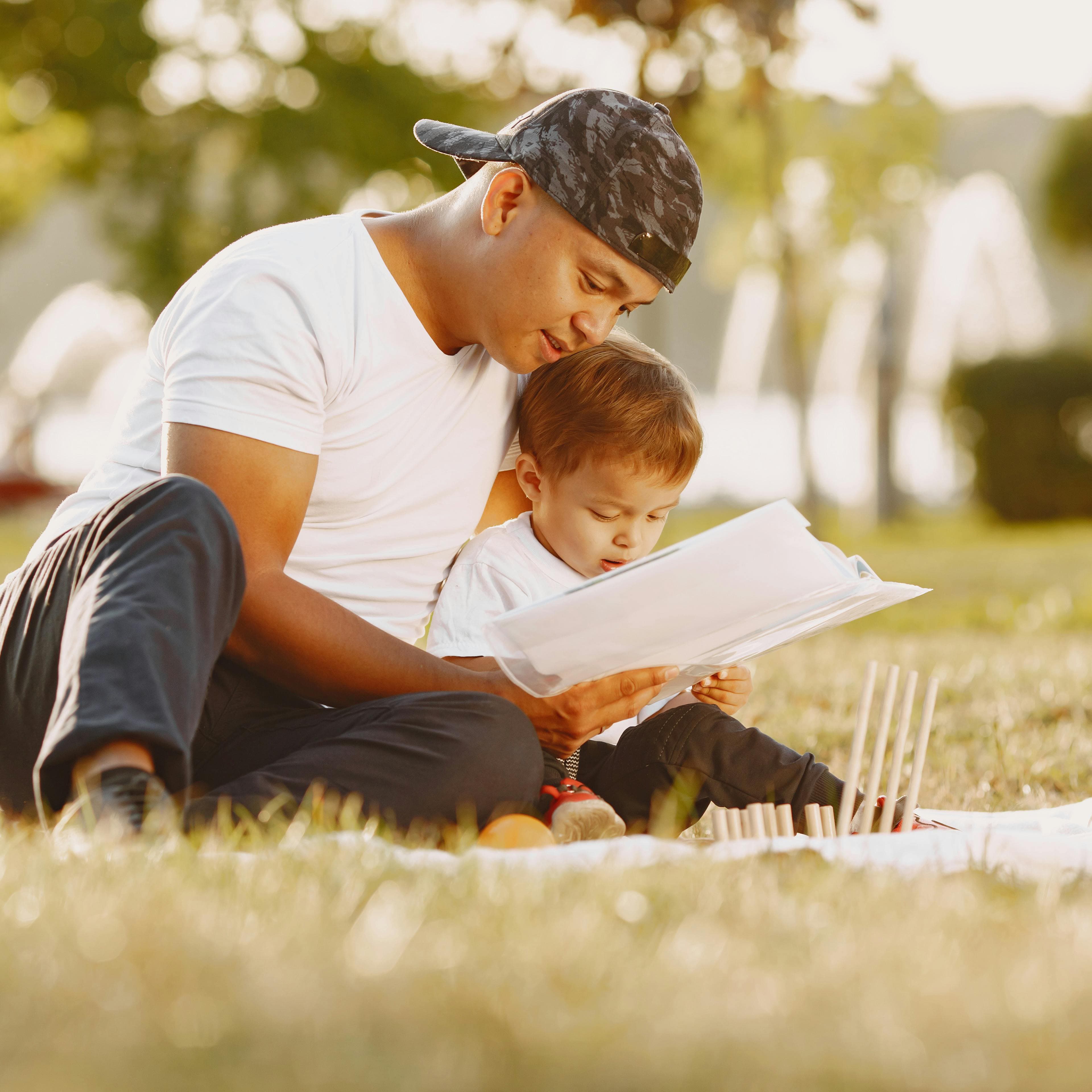 A man and a young boy reading outside at the park