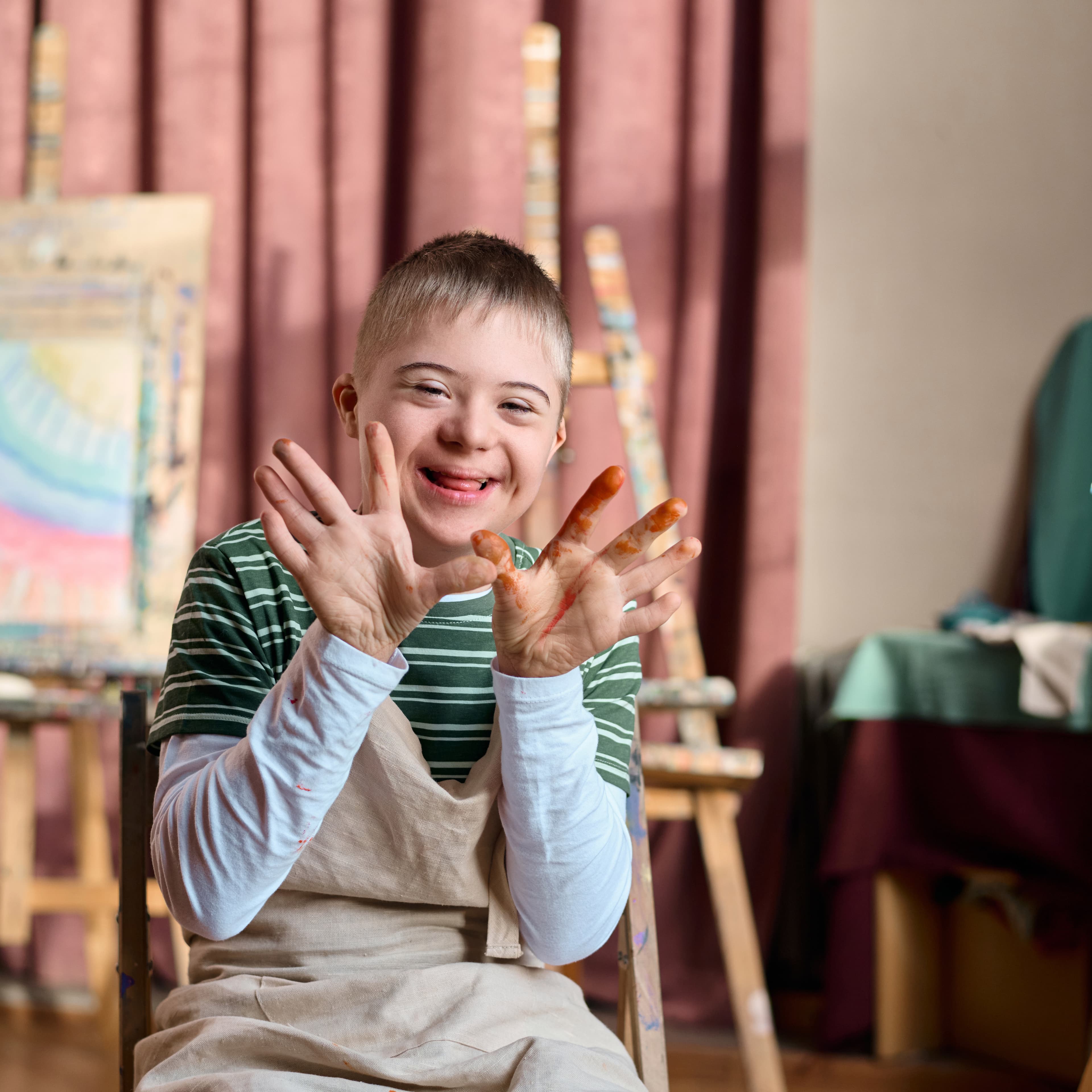 A young child displaying his messy hands during a painting class