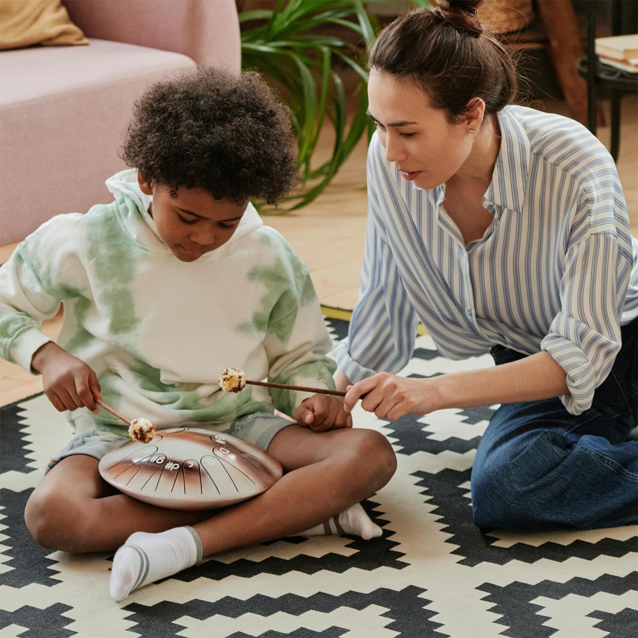 A woman and boy playing music on a steel drum